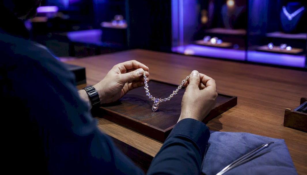 Hands using tablet amidst jewelry workbench