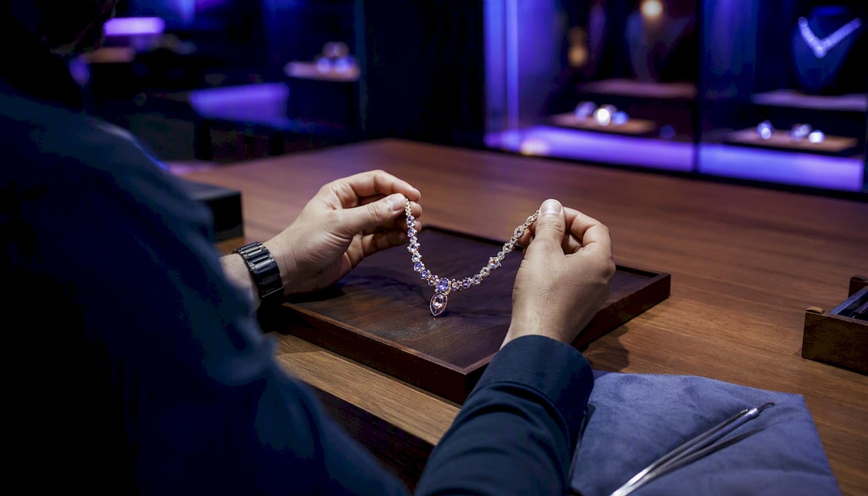 Hands using tablet amidst jewelry workbench