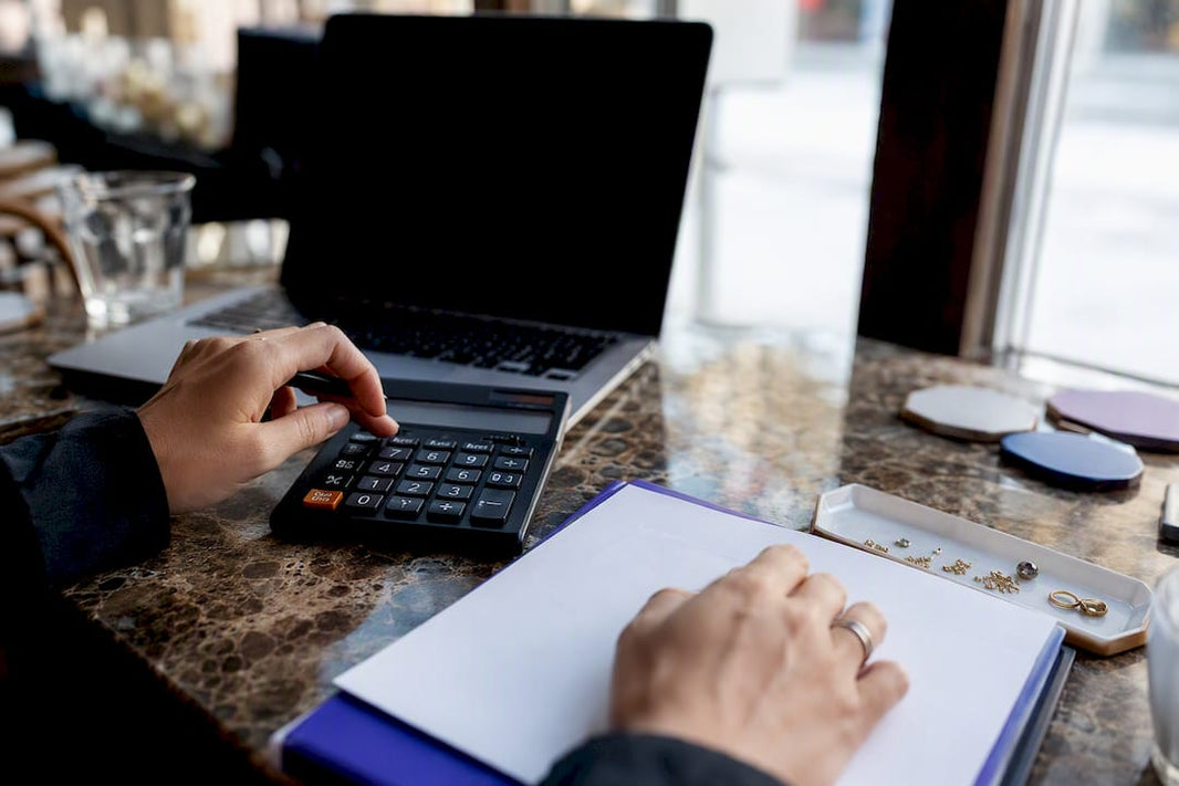 Hands calculating jewelry pricing at worktable