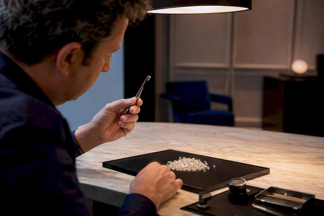 Hands sorting loose diamonds in lightbox