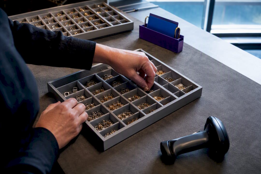 Hands organizing jewelry inventory trays